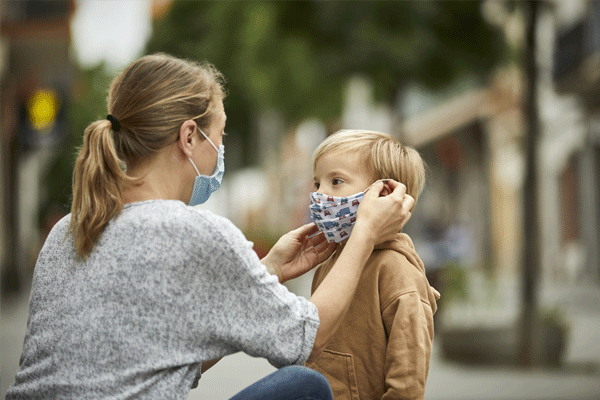 Woman putting mask on child to protect from COVID-19